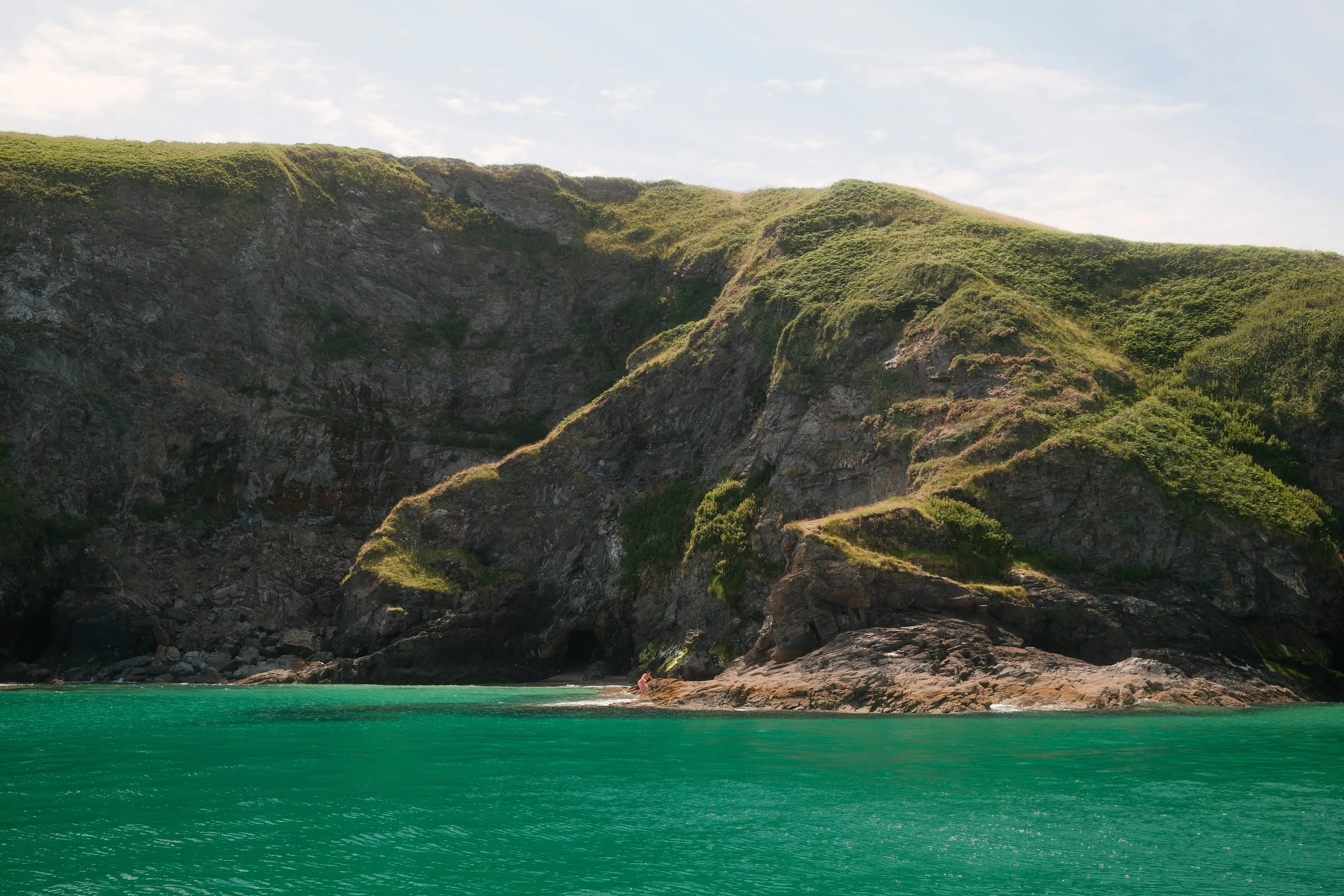 Green cliffs dropping into clear water.