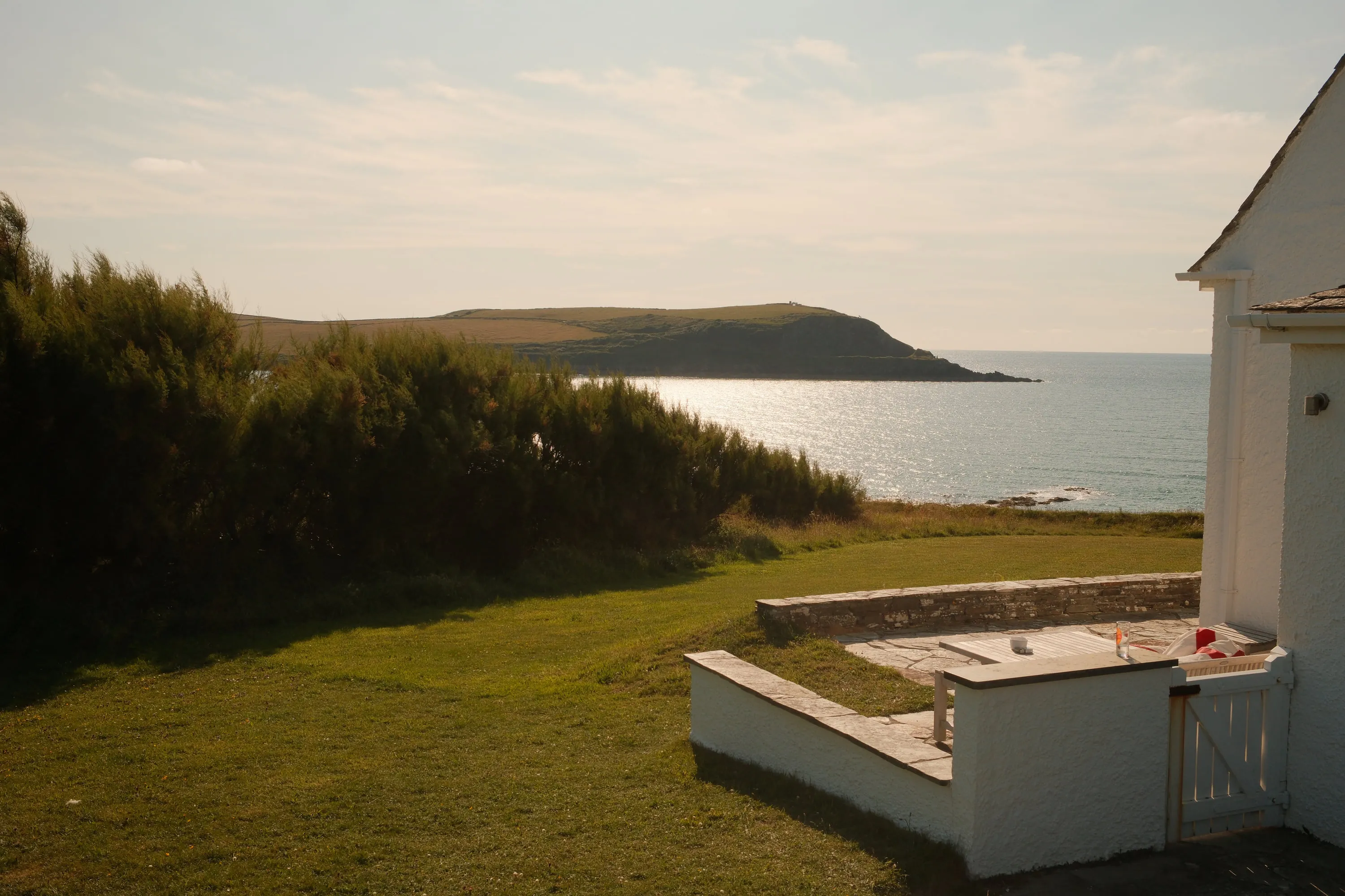 A white house on the grass above the sea.